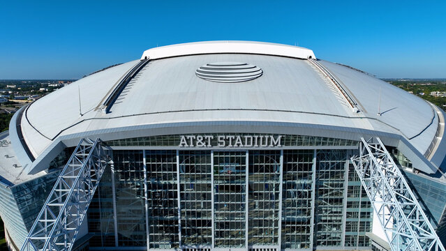 Aerial drone photo of AT&T Stadium in Arlington, Texas, on a clear sunny day. The image captures the stadium&rsquo;s modern architectural design with its iconic retractable roof