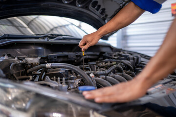 Mechanic checking engine oil level in car