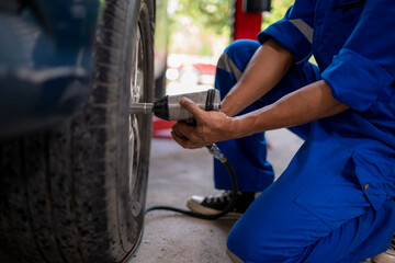 Mechanic changing car tire using pneumatic wrench