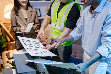 Architects and engineers work together in an office to review blueprints, exchange ideas, and refine their building plans for a contemporary construction project in an urban setting.