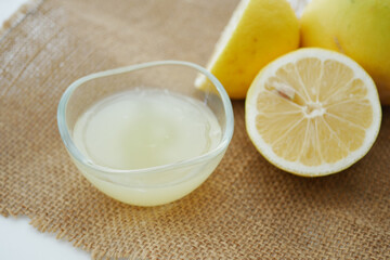 Fresh lemon juice in glass bowl with cut lemons nearby