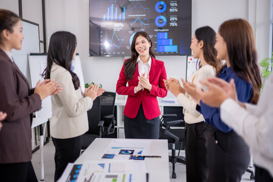 Businesswomen clapping hands to congratulate female manager after successful presentation in meeting room - Powered by Adobe