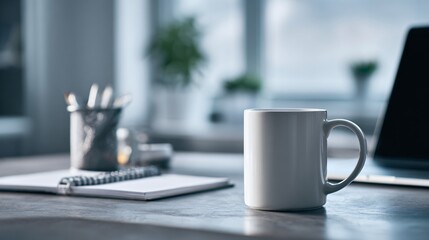 Mug notebook pen holder and laptop on a desk near a window.