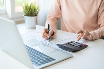 Deduction planning, debt asian young woman hand using laptop computer, calculator calculating money balance from bill and income, cost budget expenses for pay money form personal individual on table.