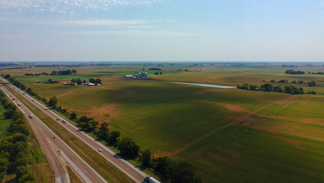 Drone shot of an interstate highway in the Midwest showing farms and open fields.