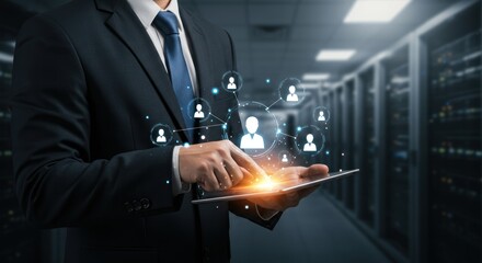 Man in suit uses tablet in server room with glowing icons.