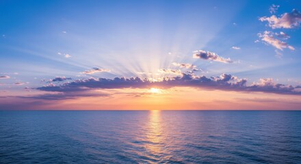 Radiant sunbeams bursting through clouds at sea horizon during sunset