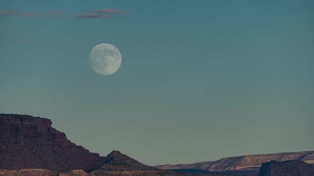Timelapse of the full moon rising over a desert rock formation cloudless sky