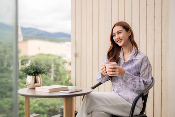 Asian adult woman sips hot coffee on home balcony enjoying peaceful morning mountain view private outdoor leisure time serene escape