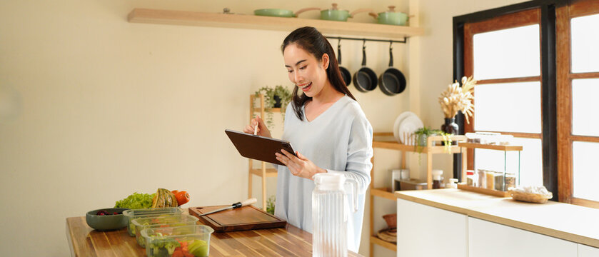 woman using digital tablet for recipe guidance while preparing healthy meals on kitchen counter.