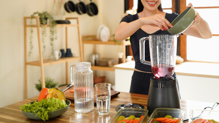 A woman adds fresh blueberries to a blender. Fresh berry smoothie preparation, Woman, hands or blender with blueberries or fruit for smoothie or healthy diet in home. © Stella 16