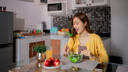 Asian adult woman eat fresh green salad home kitchen promote healthy lifestyle wellness well-being modern comfortable environment
