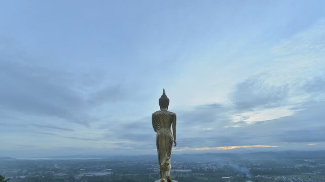 Time lapse of Golden big buddha statue standing on hill with city at Wat Phra That Kao noi, Nan, Thailand

