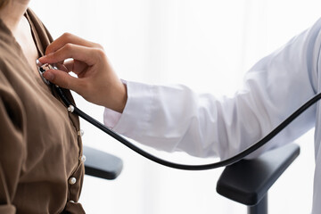 Doctor using a stethoscope checking patient stethoscope putting beat heart diagnose medical checkup cardiologist in examination room.