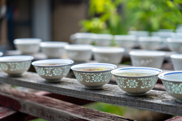 A row of traditional Chinese porcelain tea cups on a wooden shelf