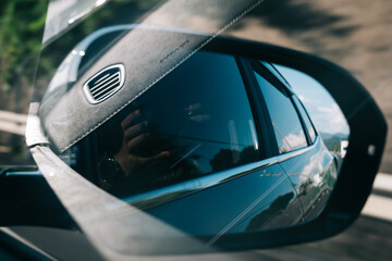 Obraz premium Side view mirror reflection showing a person taking a photo