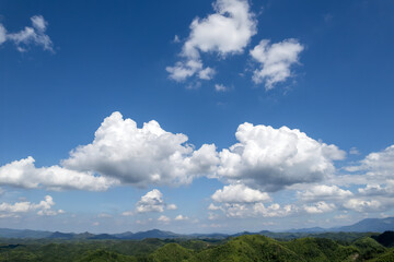 Blue sky with white clouds over green mountain ranges