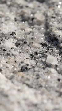 Closeup of a light gray rock with small shiny reflective surfaces and dark specks