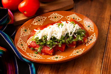 Entomatadas. Also known as Enjitomatadas, a typical dish of Mexican cuisine prepared with corn tortilla, tomato sauce and stuffed with shredded chicken meat. Classic homemade recipe.