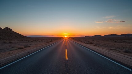 A long road stretching into the distance with the sun setting in the background over the horizon