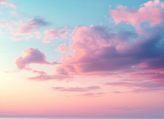 Obraz premium Soft pastel pink and purple clouds scattered across a clear blue sky during a calm sunset or sunrise