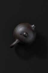 Ceramic teapot with lid and spout, top view on dark background