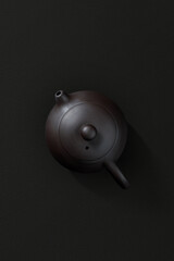 Ceramic teapot with lid and spout, top view on dark background