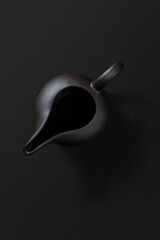 Ceramic teapot with lid and spout, top view on dark background