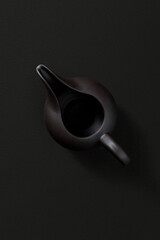 Ceramic teapot with lid and spout, top view on dark background