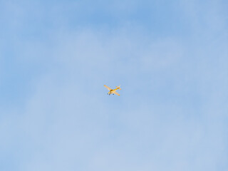 Small ultralight airplane with overhead wing and single propeller flying in sunset sky.