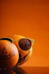 vertical image of pumpkin pals wearing sunglasses against a vibrant orange backdrop, perfect for your Halloween designs and festive holiday promotions