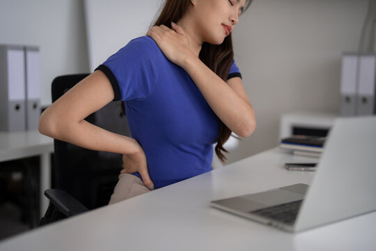 Adult Asian woman desk work pain back neck shoulder strain office setting laptop computer screen time physical discomfort bad posture health issues