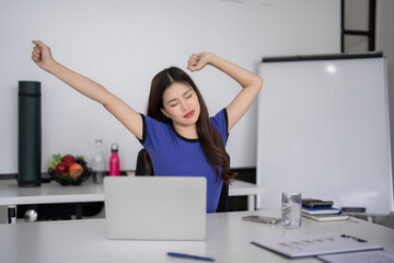 Asian adult woman stretches remote worker home office desk laptop use business wellbeing pause work stress relieve fatigue productivity focus