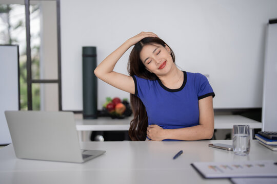 Asian adult woman stretching neck for wellness during remote work break at home office desk promoting self care and productivity