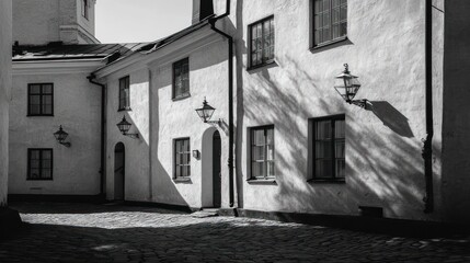 Cobblestone courtyard with old white buildings, lit by the sun, creates dynamic shadows