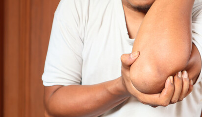 Pain in the elbow. The man holds his hand. Close up.