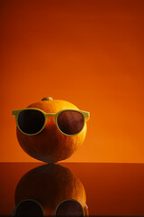 Cool pumpkin wearing sunglasses reflecting on orange surface for fun fall vibes and autumn celebrations, perfect for festive designs and creative projects
