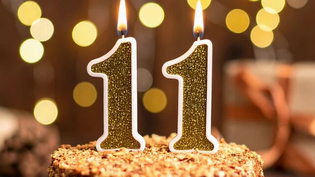 A cake with two candles lit, showing the number eleven. Bokeh background