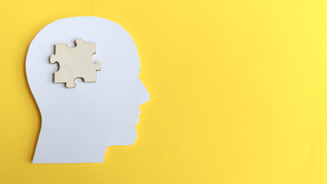 Human head silhouette with a wooden jigsaw puzzle piece inside, symbolizing problem solving, finding the solution, mental health, and missing knowledge.