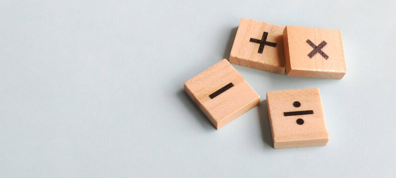 Fundamental arithmetic symbols on scattered wooden blocks against a soft blue background with clean copy space for educational and financial themes.