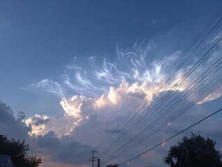 Dynamic Blue Sky with Illuminated High Clouds and Diagonal Power Lines During Golden Hour