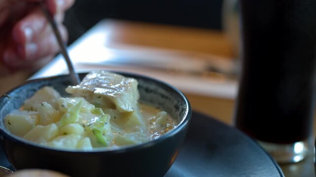 Scooping Traditional Cullen Skink Soup in Cozy Restaurant Setting