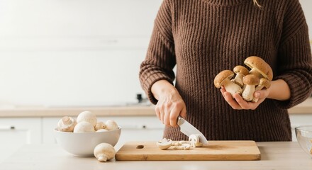 Woman slicing fresh mushrooms on a wooden cutting board in the kitchen. Preparing a healthy meal with natural ingredients