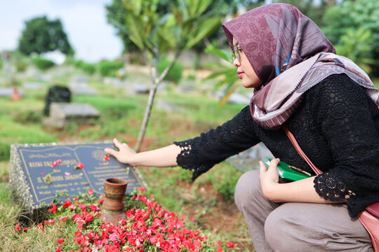 Asian Muslims woman make pilgrimage or ziarah kubur to pray for the deceased at the cemetery. 