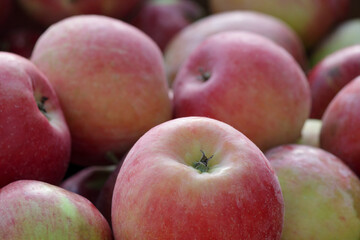Heap of fresh red and green apples close-up. Natural fruit background with ripe organic apples, healthy food concept, and harvest season texture.
