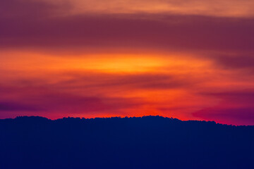 Beautiful orange and red clouds at sunrise over the mountain landscape