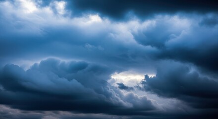 Dramatic dark storm clouds with shafts of bright sunlight breaking through the turbulent sky creating an atmospheric and moody natural landscape