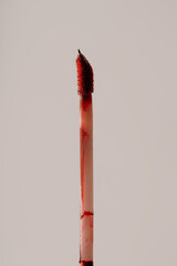 Macro of makeup sponge covered in red liquid lipstick on light background. Beauty texture and cosmetic concept.