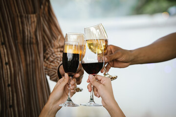 Close-up of friends clinking glasses of beer and wine during an outdoor barbecue party, celebrating and enjoying good times together.