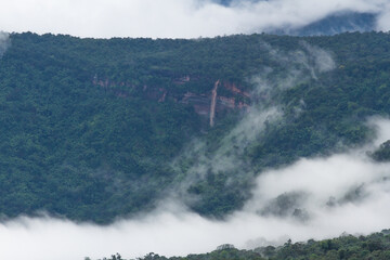 waterfall in mountain forest with cloud around 